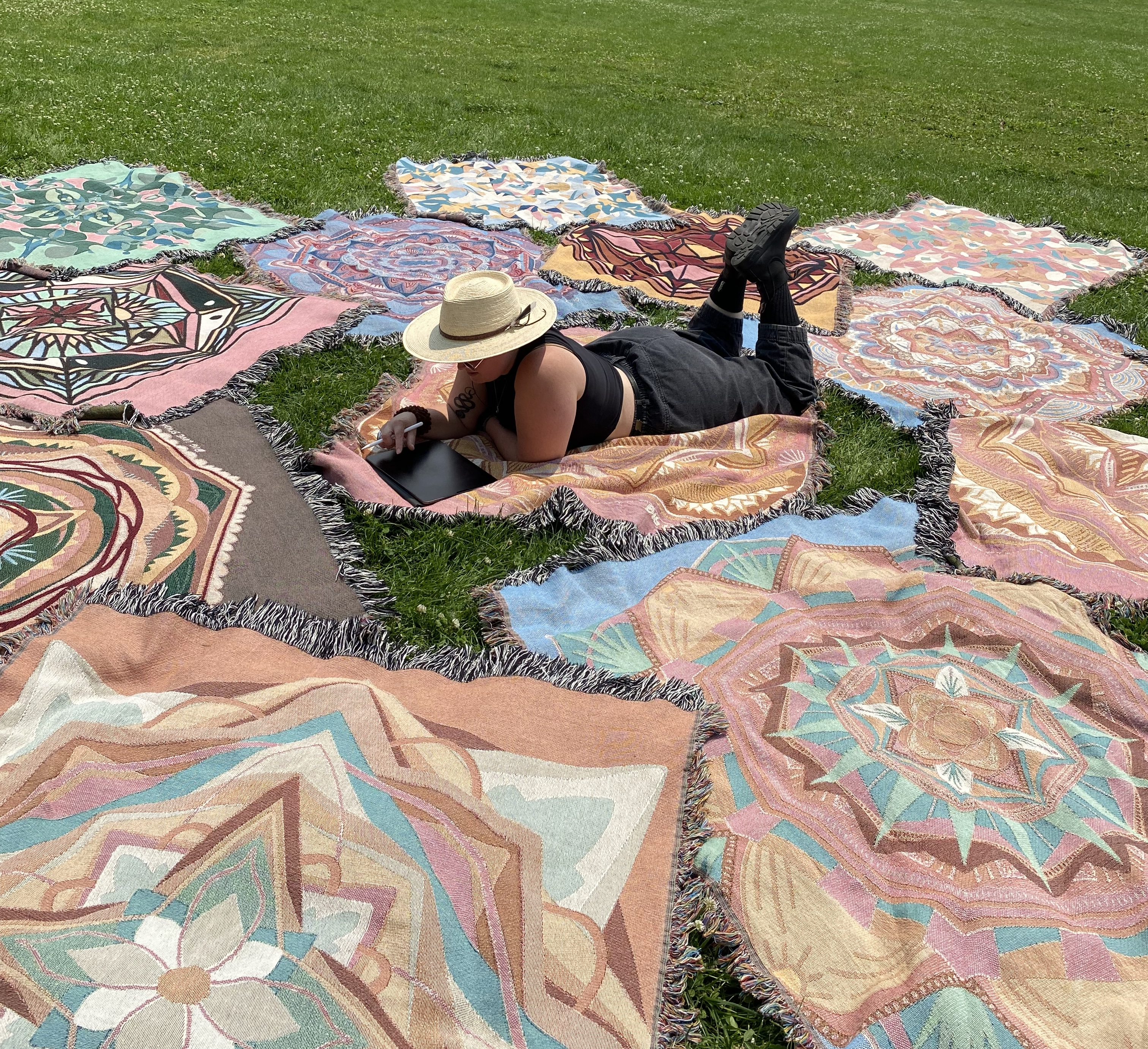 Mackenzie lies amongst a dozen ritual blankets in the grass.