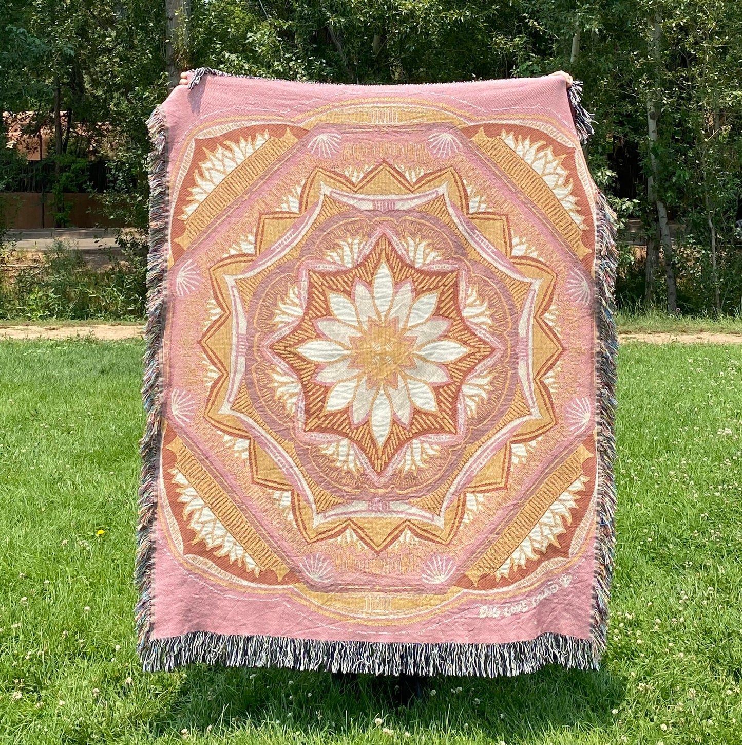 A colorful patterned pink and golden mandala blanket with fringe