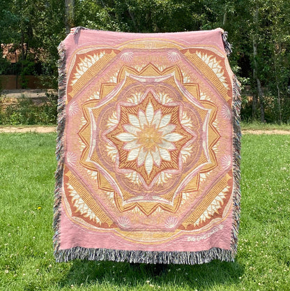 A colorful patterned pink and golden mandala blanket with fringe