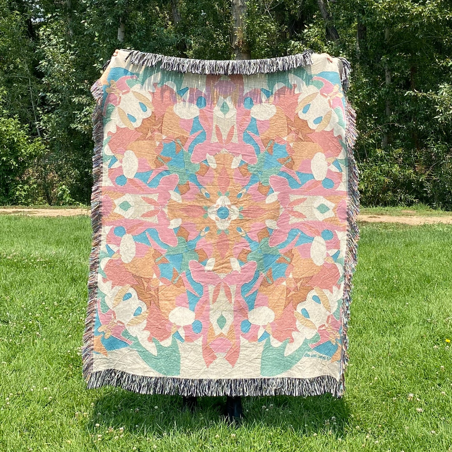 A colorful patterned kaleidoscope patterned blanket with fringe