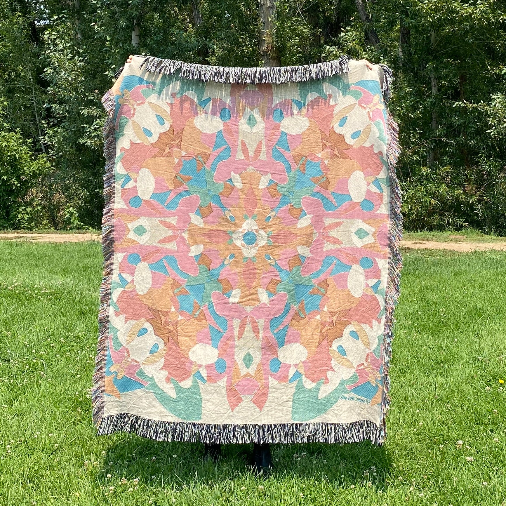 A colorful patterned kaleidoscope patterned blanket with fringe
