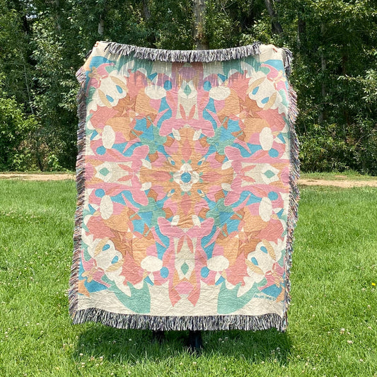 A colorful patterned kaleidoscope patterned blanket with fringe