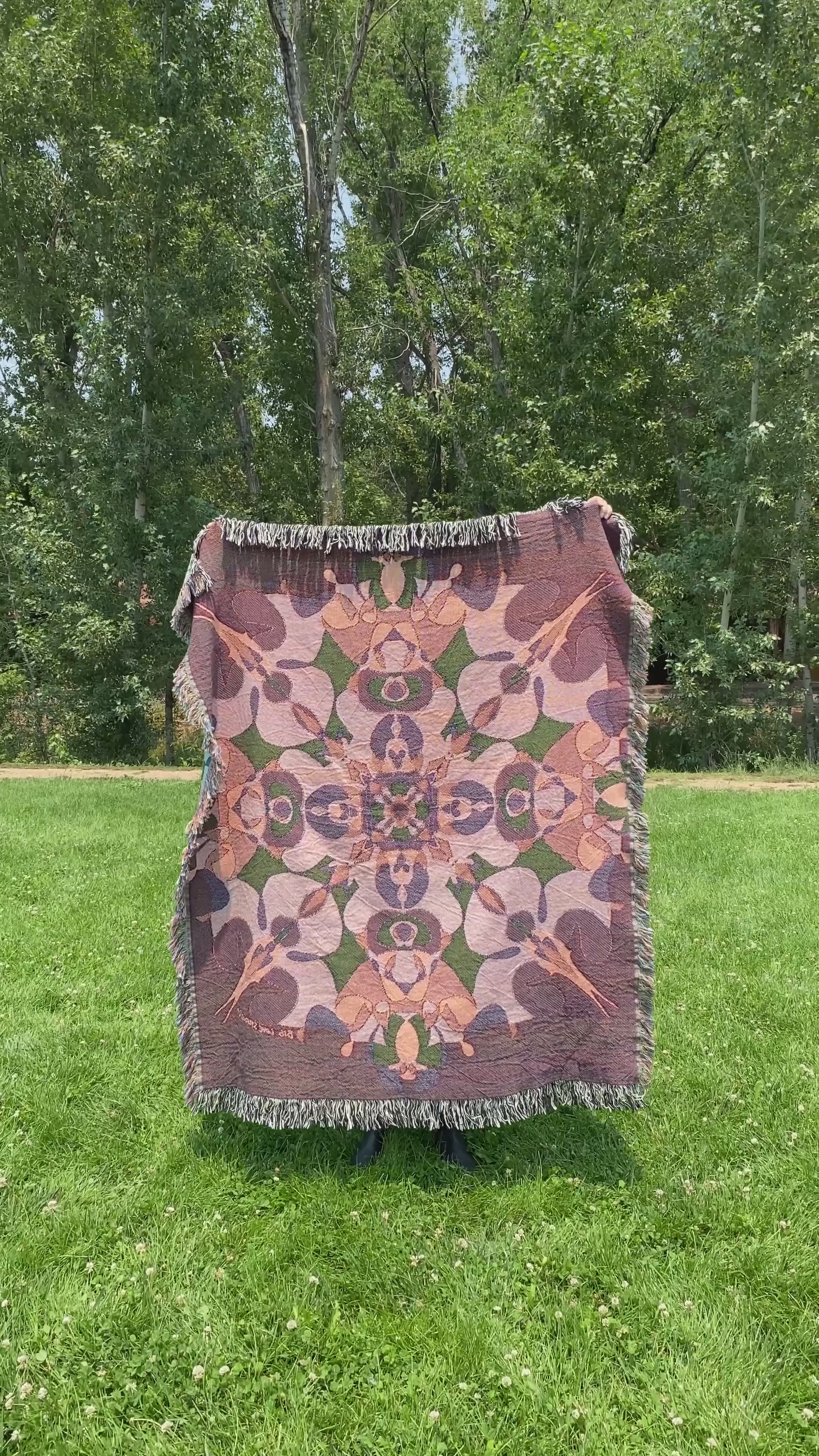 Mackenzie wraps a brightly colored kaleidoscope woven blanket with fringe around her