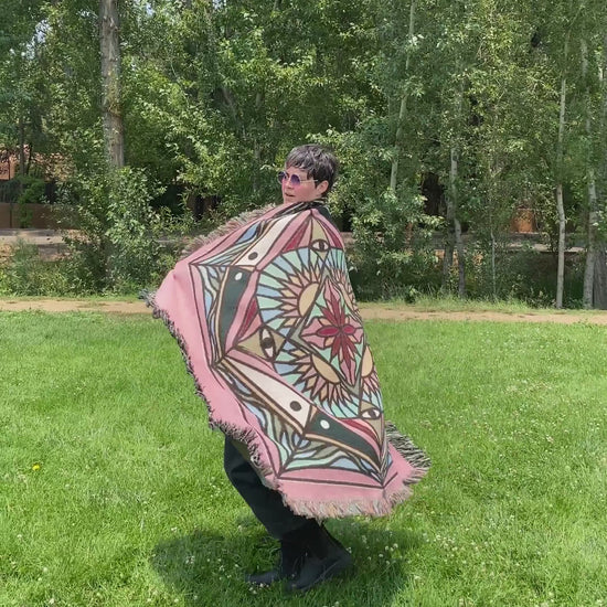 Video of Mackenzie wrapped in a brightly colored mandala woven blanket.
