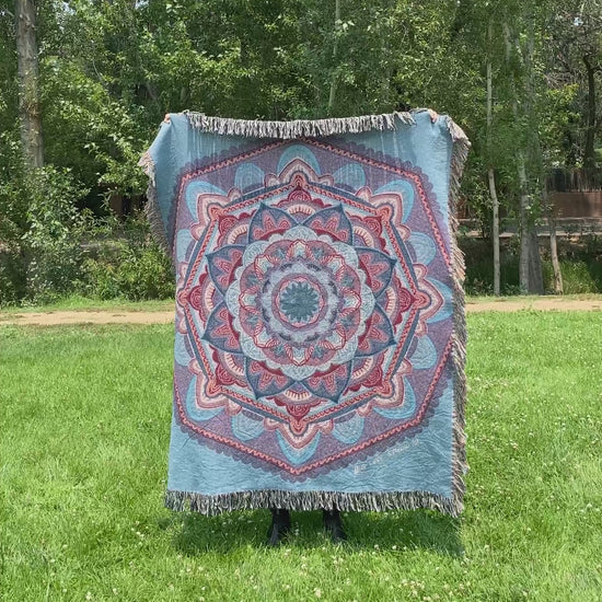 Mackenzie flips a blue mandala woven blanket with fringe to see the front and back