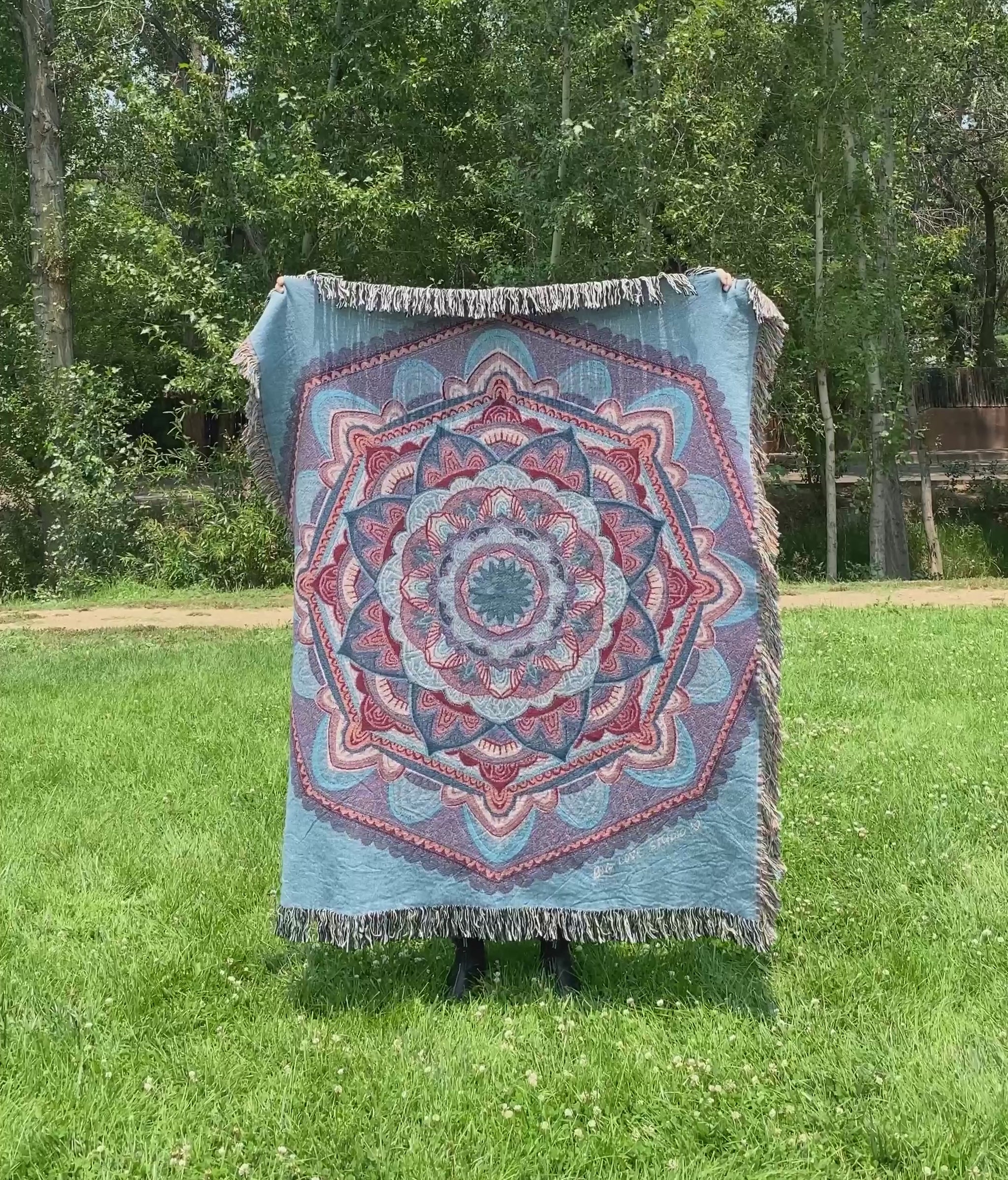 Mackenzie flips a blue mandala woven blanket with fringe to see the front and back