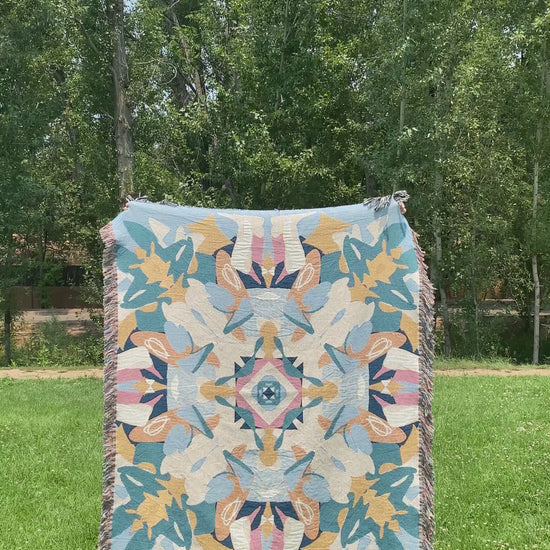 Video of a blue and yellow colorful kaleidoscope patterned woven blanket being turned around.