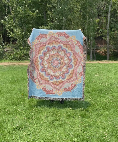 Mackenzie flips a brightly colored mandala woven blanket with fringe to see the front and back