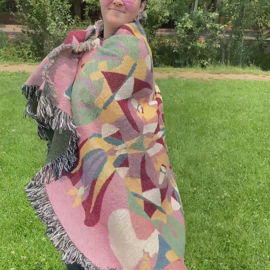 Mackenzie wraps a brightly colored kaleidoscope woven blanket with fringe