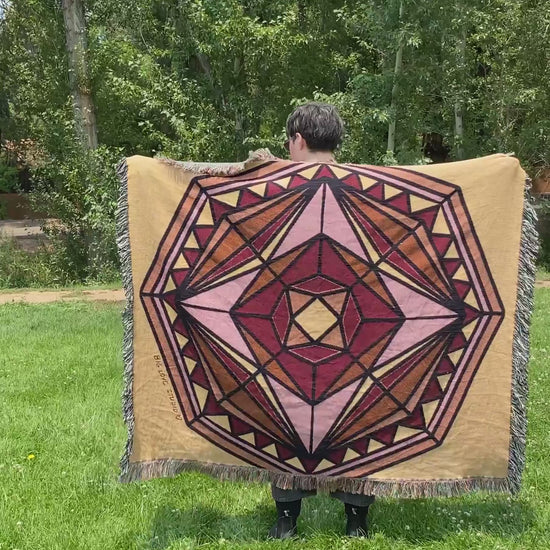 Mackenzie flips a mandala woven blanket with fringe to see the front and back