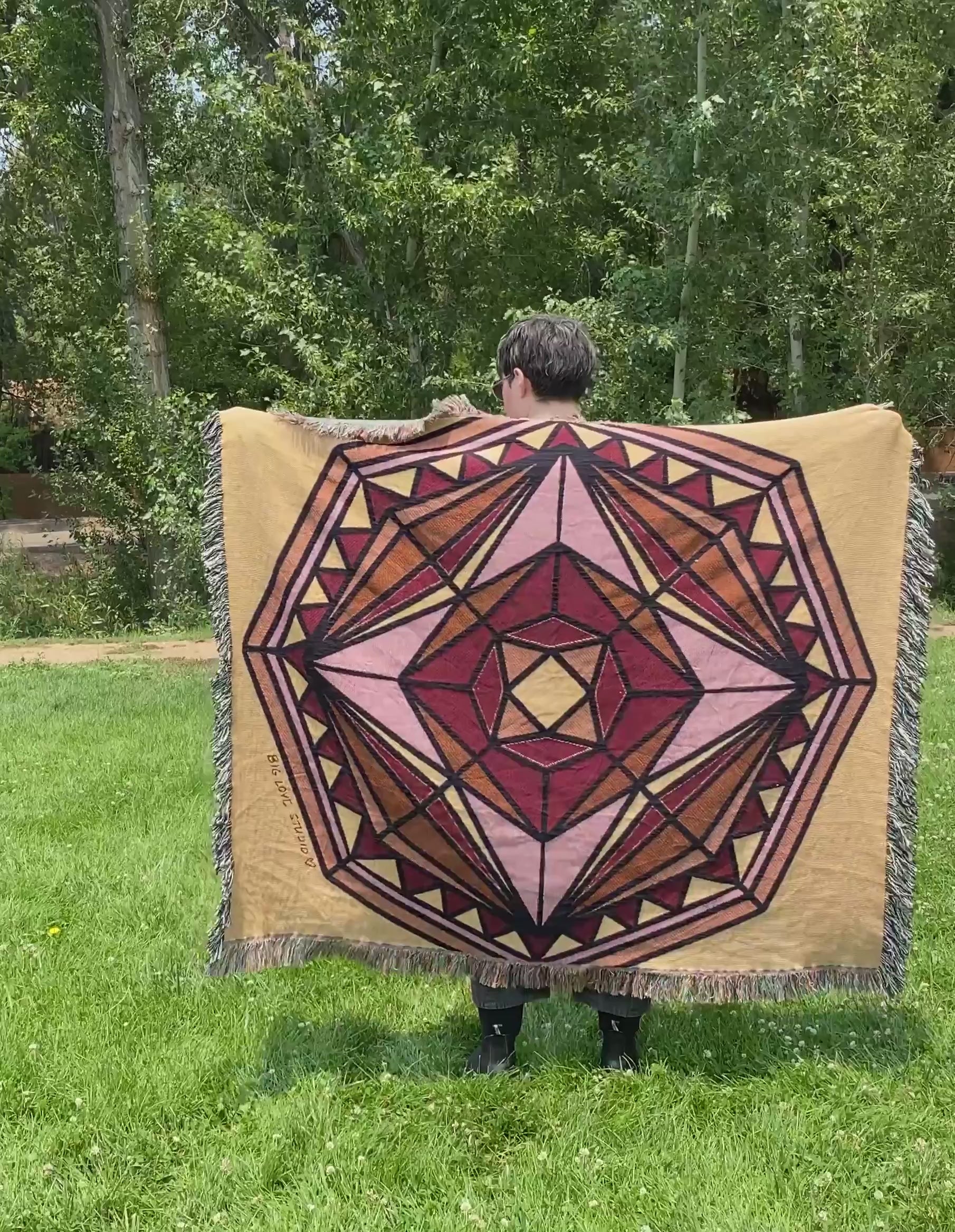 Mackenzie flips a mandala woven blanket with fringe to see the front and back