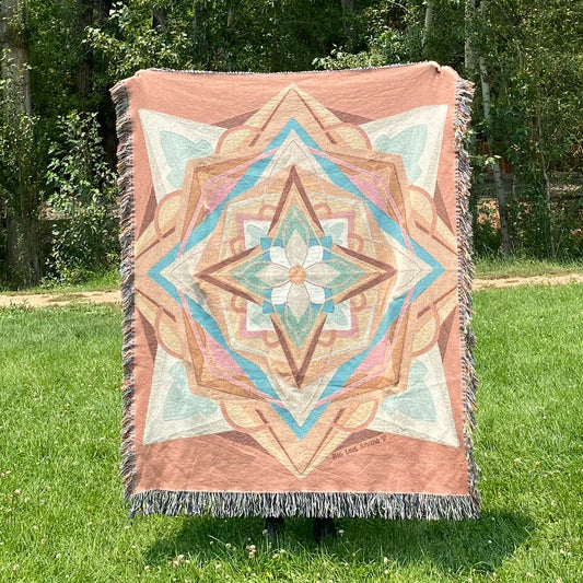 A colorful mandala patterned blanket with fringe in coral and greens