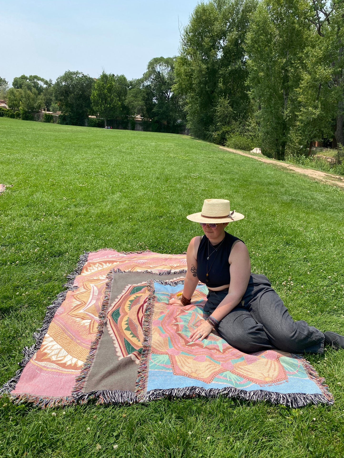 Mackenzie sits on the three sizes of ritual blankets in a grassy park