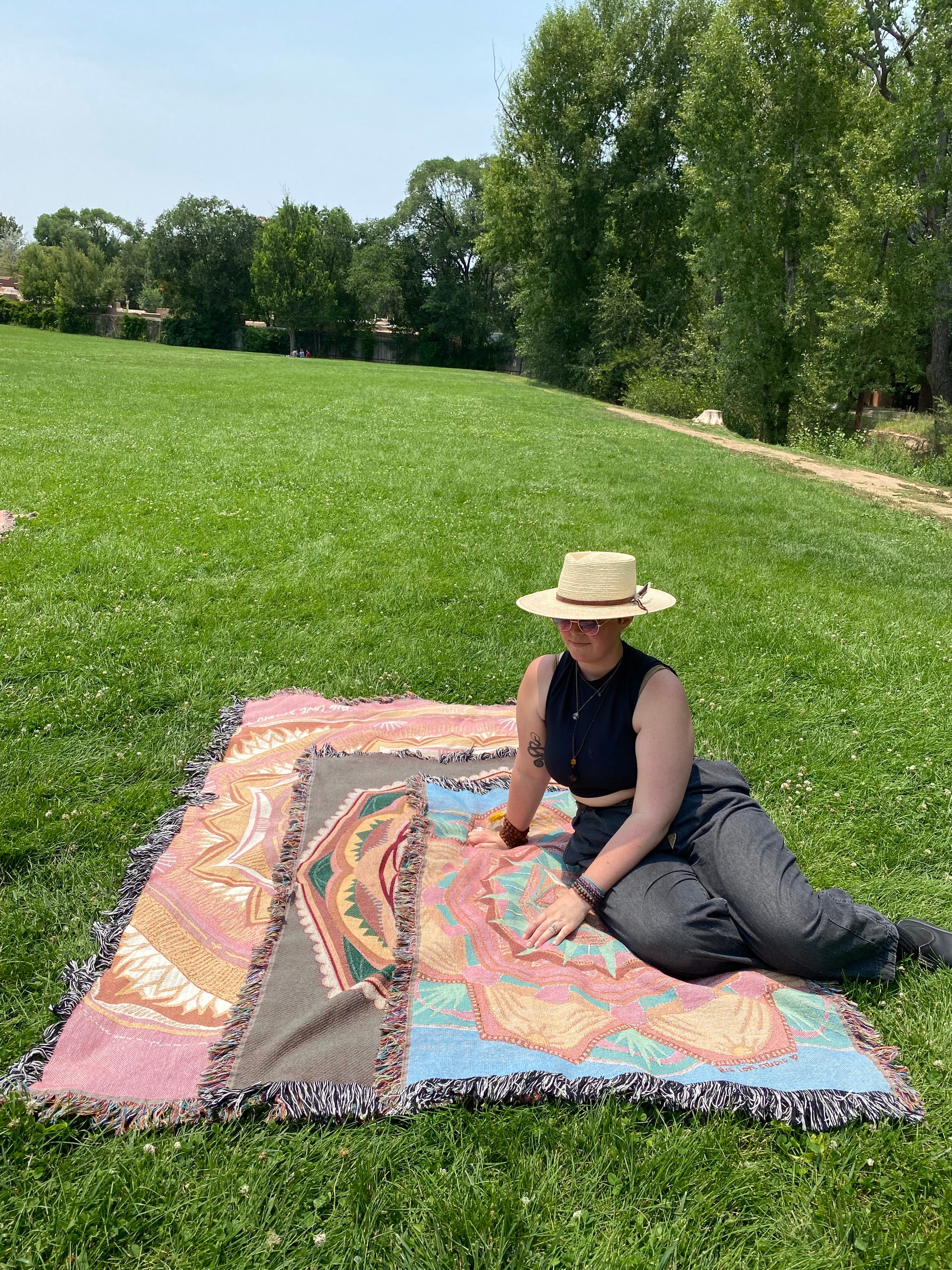 Mackenzie sits on the three sizes of ritual blankets in a grassy park