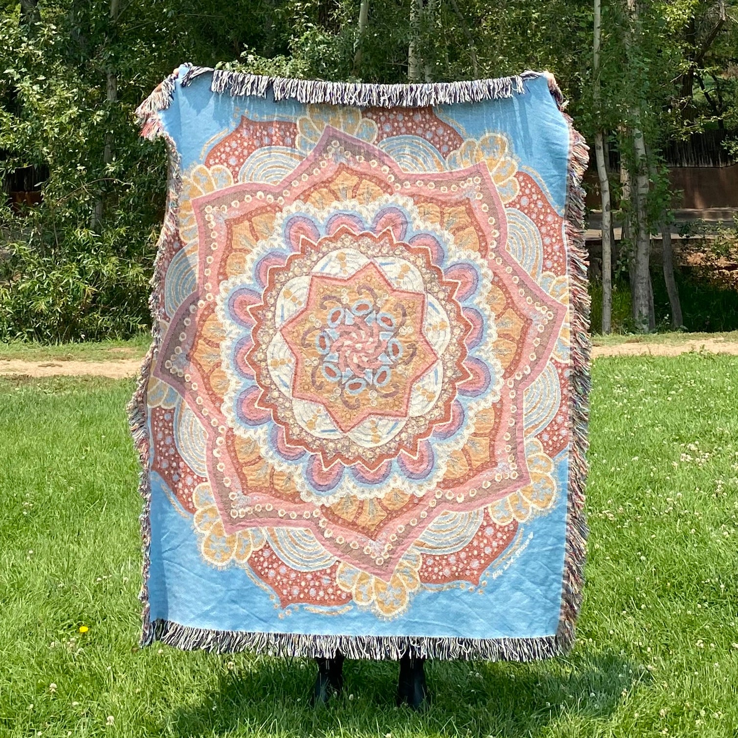 A blue and pink mandala woven blanket with fringe